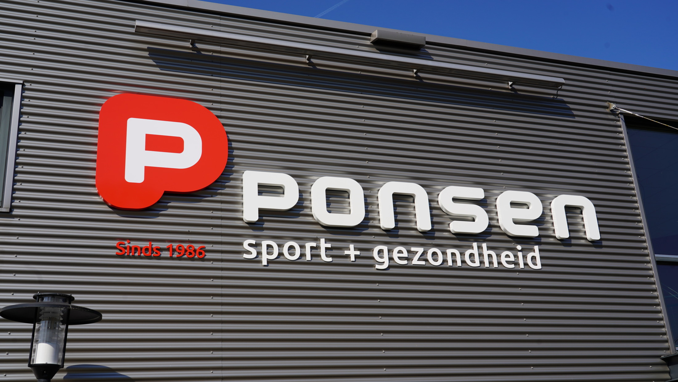 Grote tweekleurige Acrylox gevelletters 'Ponsen Sport & Gezondheid' geplaatst door Mull2media op de damwandgevel in Dinxperlo.