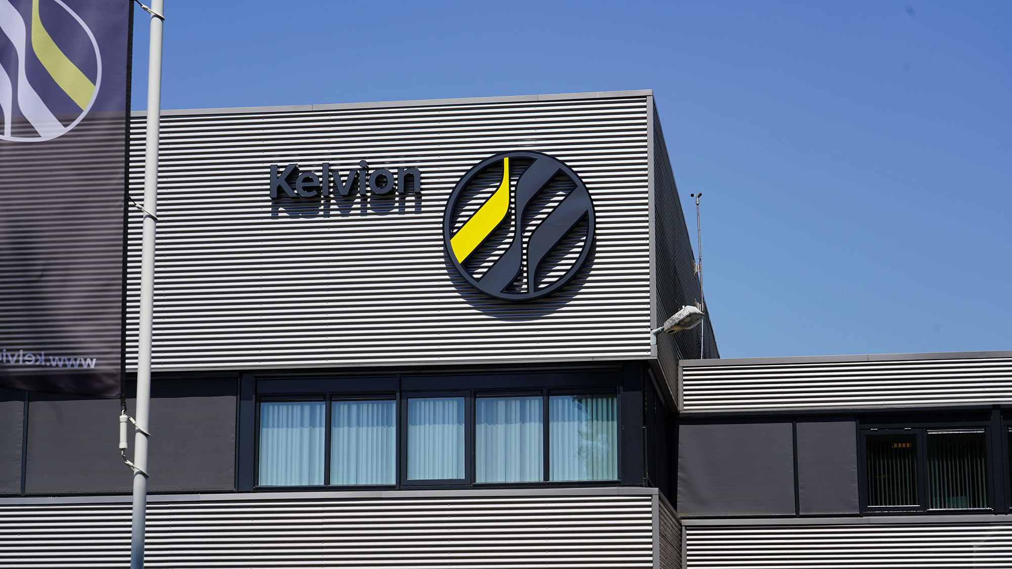 Kantoorpand van Kelvion met gevellogo en Kelvion-vlag in de nieuwe huisstijl Kantoorpand van Kelvion met gevellogo en Kelvion-vlag in de nieuwe huisstijl